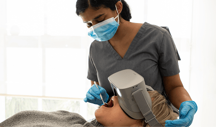 Dr. Diluni examining a patient’s teeth while the patient lies back in the dental chair wearing VR goggles for a relaxed and immersive experience.