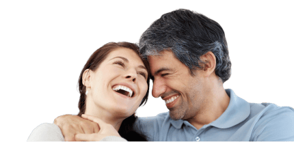 Smiling couple embracing and laughing together, showcasing healthy, confident smiles, representing the life-changing impact of tooth replacement treatments.