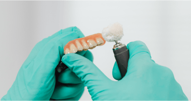 Close up of a dental professional polishing a beautifully crafted set of natural-looking dentures.