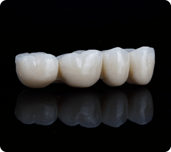 Close up of a dental bridge on a black background.