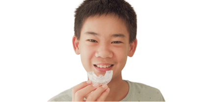 Smiling boy holding a dental mouthguard, commonly used for sports protection or teeth grinding prevention.