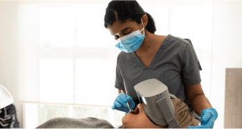 Dr. Diluni inspecting a Mulgrave Dental Group patient's mouth with a mouth mirror while the patient wears VR goggles.