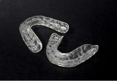 Two clear dental splints on a black background.