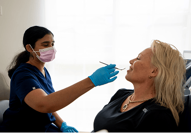Dr. Diluni holding a mouth mirror while in a dental consultation with a Mulgrave Dental Group patient.