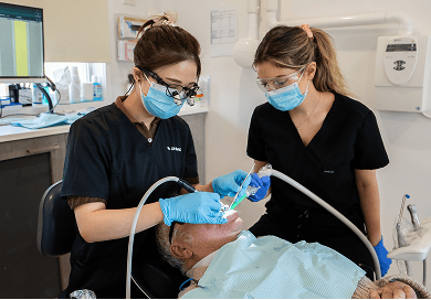 Mulgrave Dental Group dentist and dental assistant cleaning a patient's teeth during a professional dental cleaning procedure.