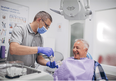 A dentist showing a dental implant tooth model to a patient.