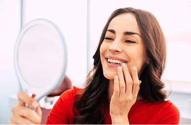 Smiling woman looking at her teeth in the mirror.