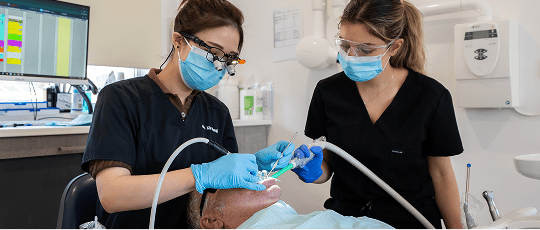 Mulgrave Dental Group dentist and dental assistant cleaning a patient's teeth during a professional dental cleaning procedure.