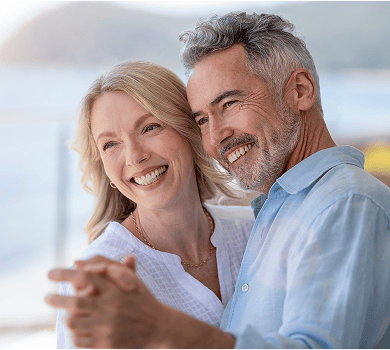 An older couple smiling, showing off their beautiful smiles while dancing.