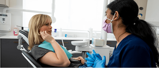 A Mulgrave Dental Group patient pointing at pain in their jaw while in a consultation with a Dr. Diluni.