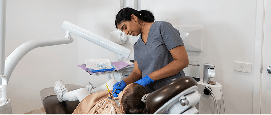 Dr. Diluni gently examining a young child's teeth.
