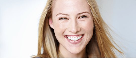 Smiling woman with a gummy smile, where excessive gum tissue is visible above the upper teeth.