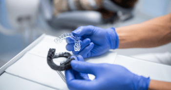 Close up of a dentist holding clear aligners.