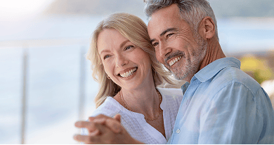 An older couple smiling, showing off their beautiful smiles while dancing.