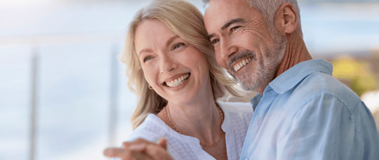 An older couple smiling, showing off their beautiful smiles while dancing.