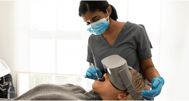 Dr. Diluni gently inspecting a Mulgrave Dental Group client's teeth while they relax and use VR goggles.