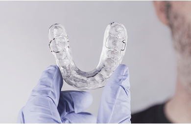 Close up of a gloved hand holding a dental splint.