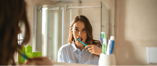 Woman brushing her teeth at home.
