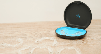 Invisalign case with an Invisalign aligner in it, on the table with more Invisalign aligners.