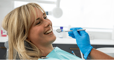 Smiling patient at Mulgrave Dental Group sitting in the dental chair while a dentist holds a mouth mirror during a check-up.
