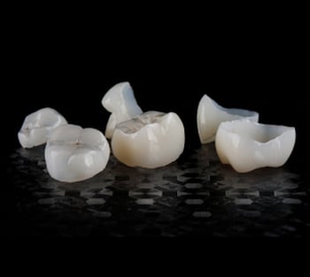 Close up of dental crowns on a black background.