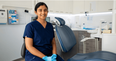 Principal dentist at Mulgrave Dental Group, Dr. Diluni Perera is smiling, seated in a modern dental clinic beside a dental chair and equipment.
