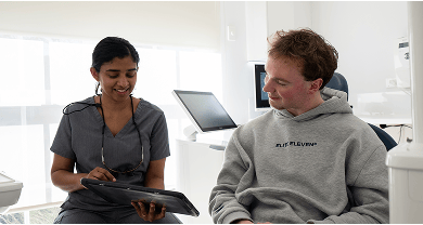 Dr. Diluni consulting with a patient, using a tablet to explain dental information during the appointment.