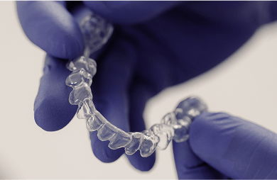 Close up of a dental splint being held by two gloved hands.
