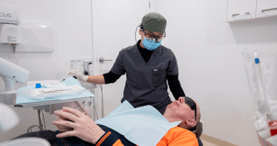 Image of Mulgrave Dental Group dentist wearing a protective face mask and medical gloves while performing a dental check-up on a patient.