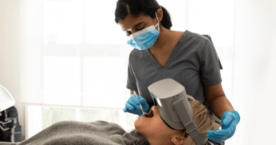 Mulgrave Dental Group dentist inspecting a patient's teeth during a check-up. The patient wears a virtual reality headset, for a comfortable and calming dental experience.