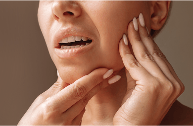 Close-up of a woman holding her jaw.