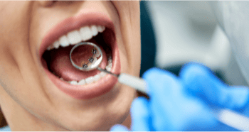 Dentist holding a dental mouth mirror revealing lingual braces on the back of the patient's teeth.