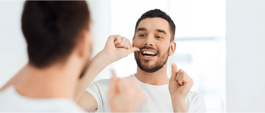 Man flossing his teeth as part of a good oral hygiene routine at home.