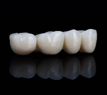 Close up of a dental bridge on a black background.