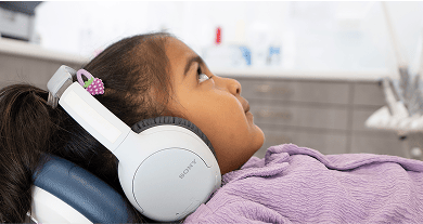 Young patient at Mulgrave Dental Group lying back in the dental chair, wearing headphones and watching a ceiling-mounted TV for a calm and comfortable dental experience.
