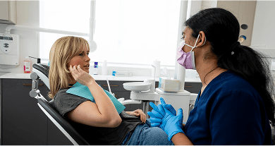 A Mulgrave Dental Group patient pointing at pain in their jaw while in a consultation with a Dr. Diluni.