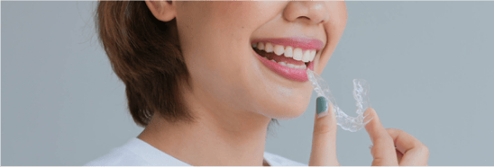 Smiling woman holding a clear aligner.