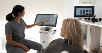 Mulgrave Dental Group’s Principal Dentist pointing at a dental X-ray scan while discussing findings with a patient, highlighting areas of concern and treatment options.