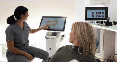 Dr. Diluni smiling and showing a patient a 3D scan of their teeth during a dental consultation.