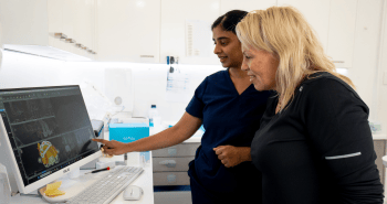 Dr. Diluni and a Mulgrave Dental Group patient looking at the computer screen together during a smile makeover consultation.