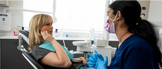 A Mulgrave Dental Group patient pointing at pain in their jaw while in a consultation with a Dr. Diluni.