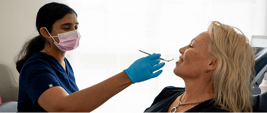 Dr. Diluni holding a mouth mirror while in a dental consultation with a Mulgrave Dental Group patient.
