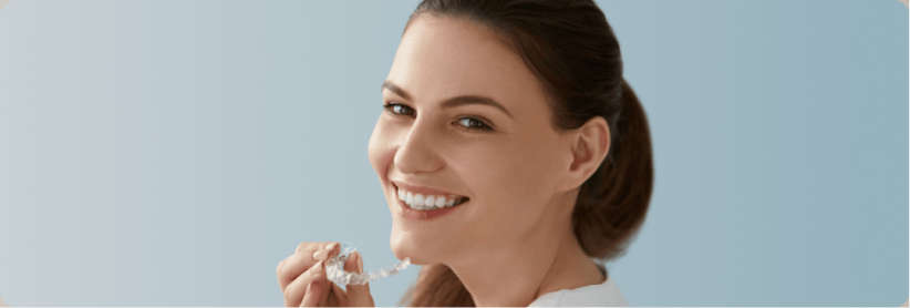 Smiling woman putting on a clear aligner.
