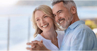 An older couple smiling, showing off their beautiful smiles while dancing.