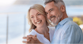 An older couple smiling, showing off their beautiful smiles while dancing.