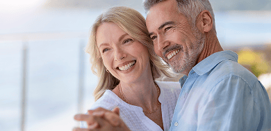 An older couple smiling, showing off their beautiful smiles while dancing.