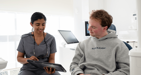 Dr. Diluni consulting with a patient, using a tablet to explain dental information during the appointment.