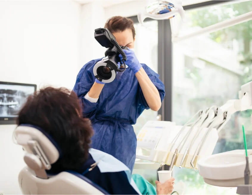 Dentist Taking Photos of Patient's Teeth while Sitting in Dentist Chair